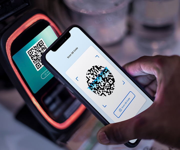 Mobile phone scanning a QR code on a digital payment device