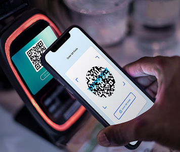 Mobile phone scanning a QR code on a digital payment device